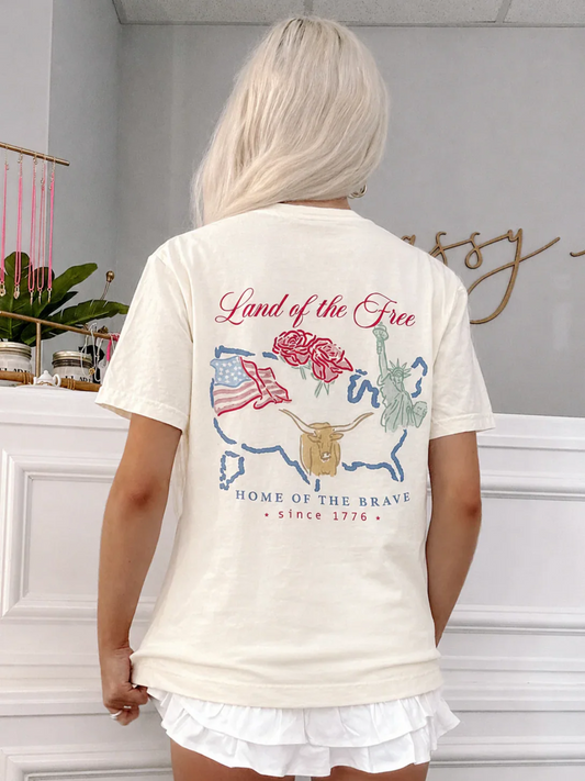 Back view of the Land of the Free Tee from Sassy Shortcake featuring USA map artwork, roses, American flag, Statue of Liberty, longhorn graphic, and Home of the Brave text.