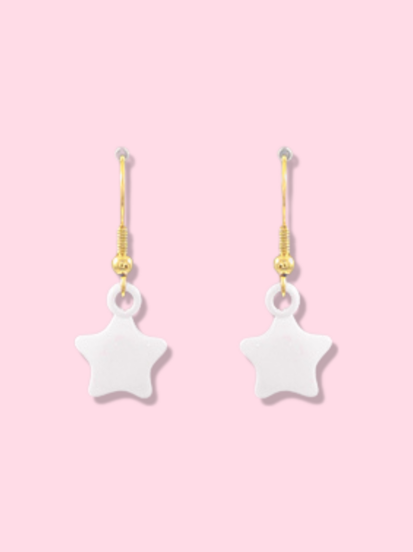 White star-shaped drop earrings with gold hoops against a pink background.