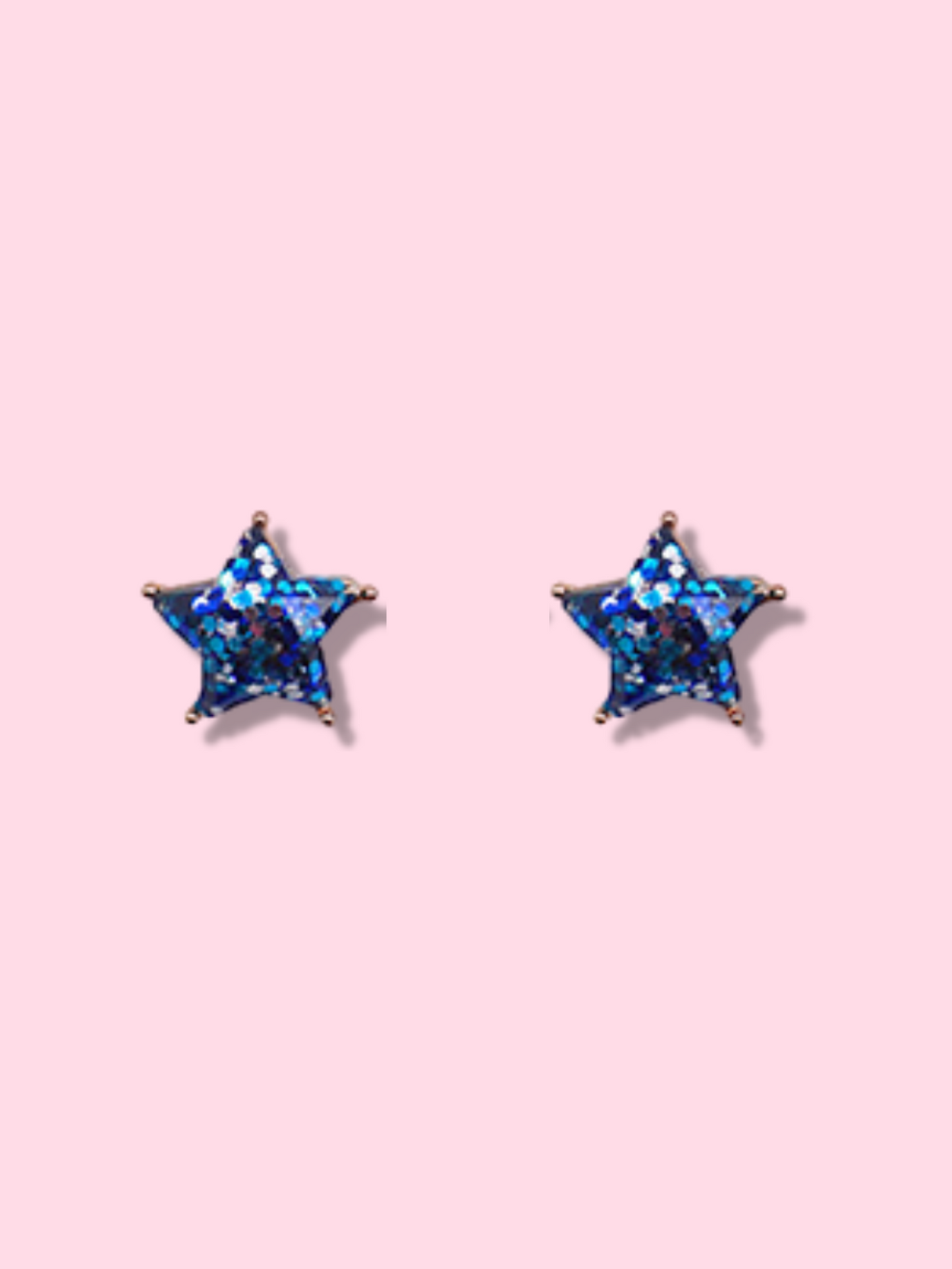 Sparkling blue glitter star stud earrings against a pink background.