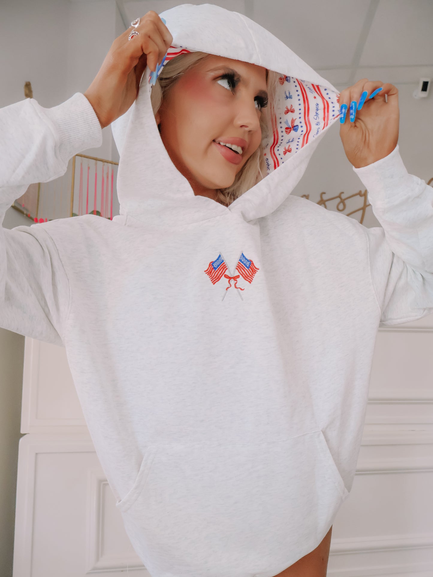 Side view of grey hoodie with lined hood featuring red, white, and blue detail.
