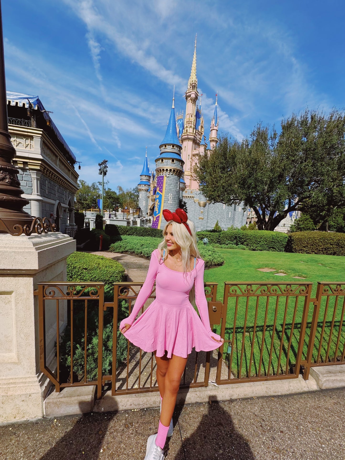 Pink dress and Minnie Mouse ears near Cinderella Castle on a sunny day.