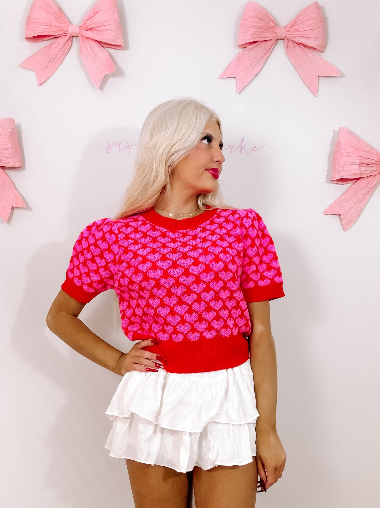 Red short-sleeve top with pink hearts, modeled against a white background with pink bows.