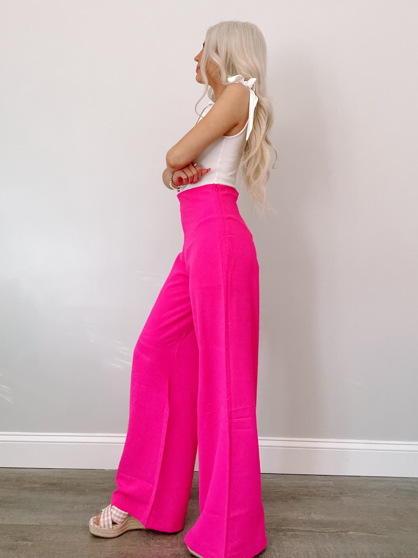 Hot pink wide-leg pants shown on a model against a white wall.