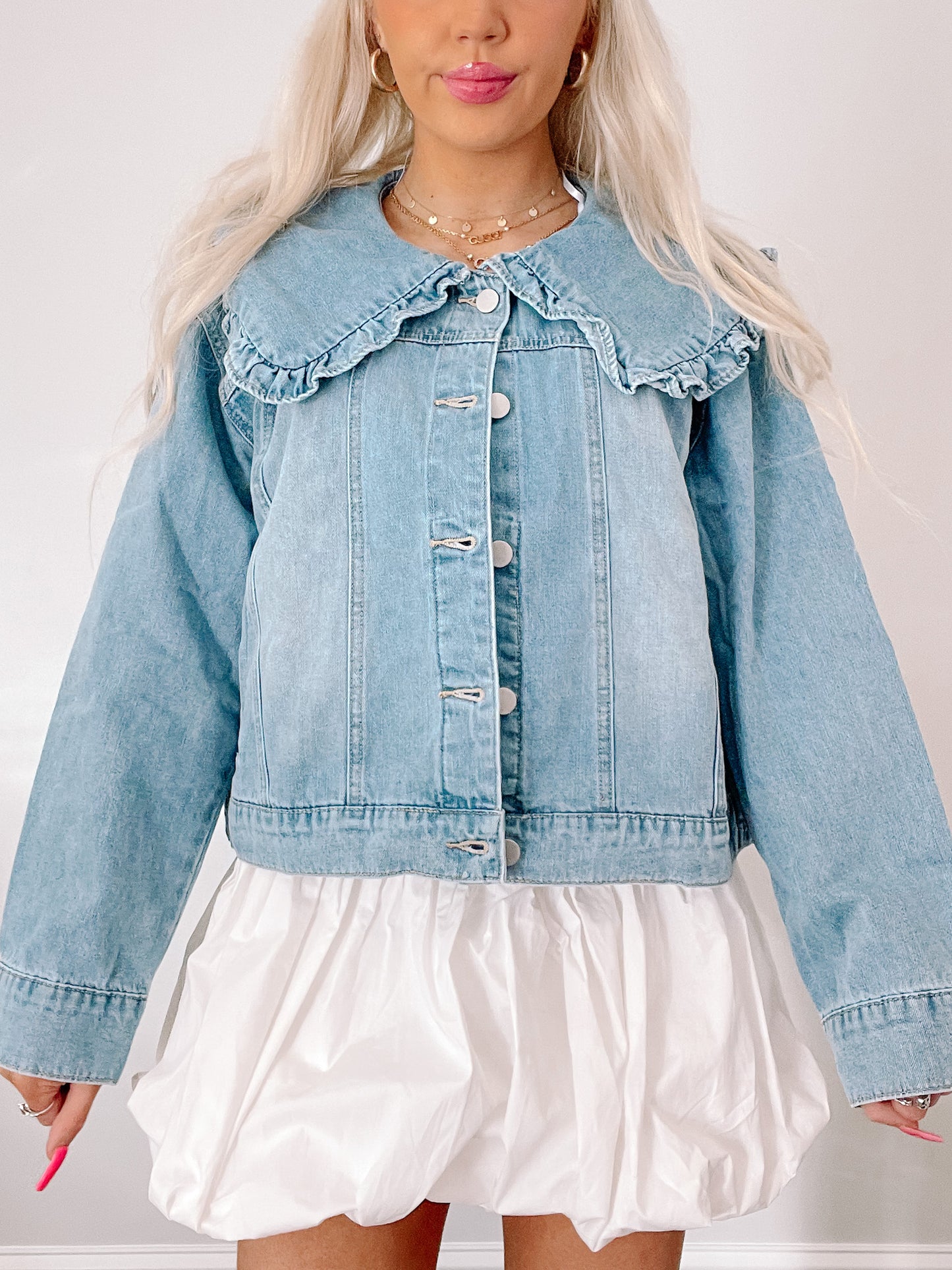 Light wash denim jacket featuring a ruffled Peter Pan collar, shown on a model.