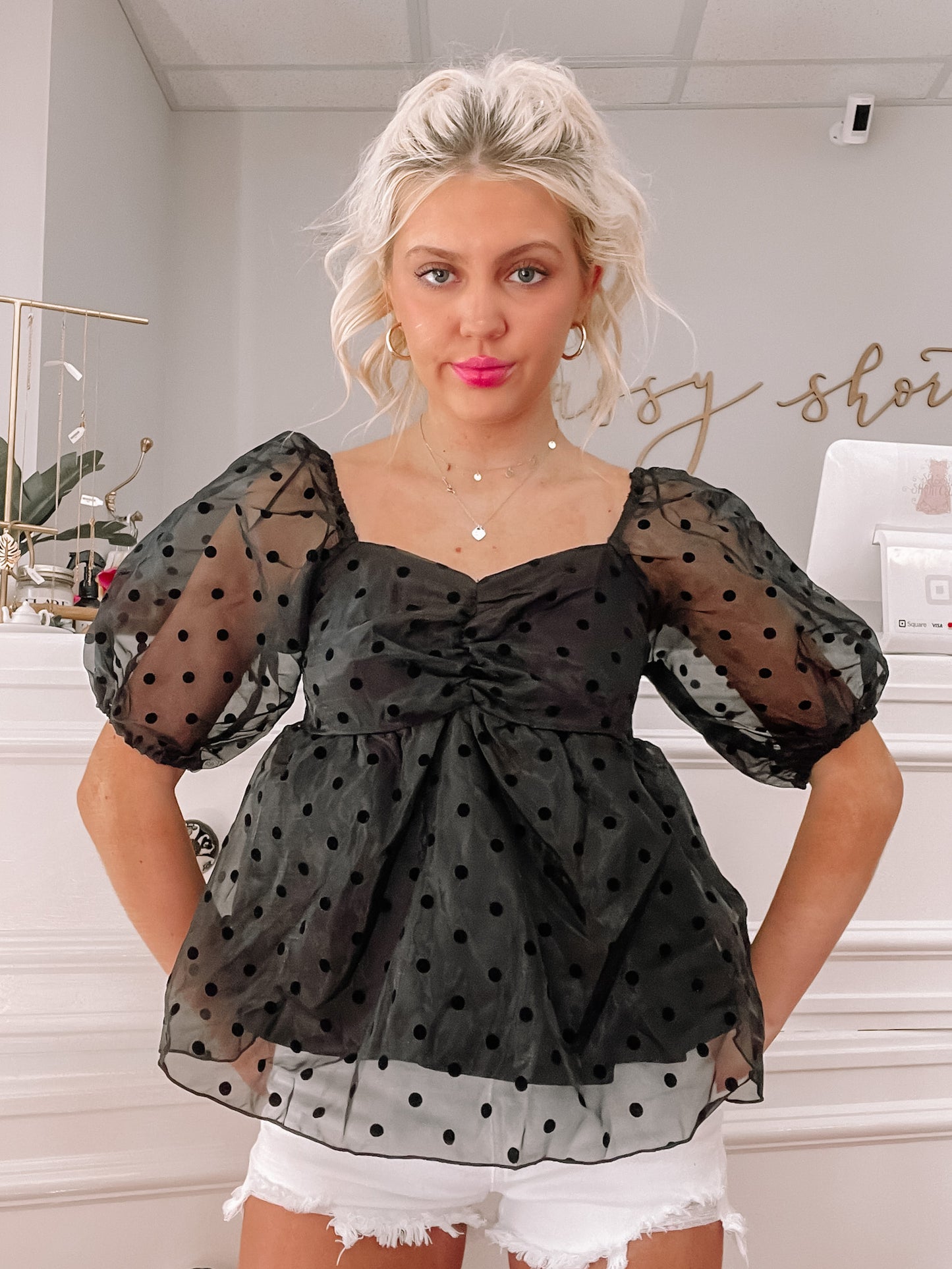Black sheer polka dot top with puff sleeves, modeled against a white background.