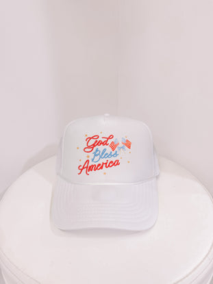White trucker hat with "God Bless America" embroidered in red and blue, featuring small American flags.