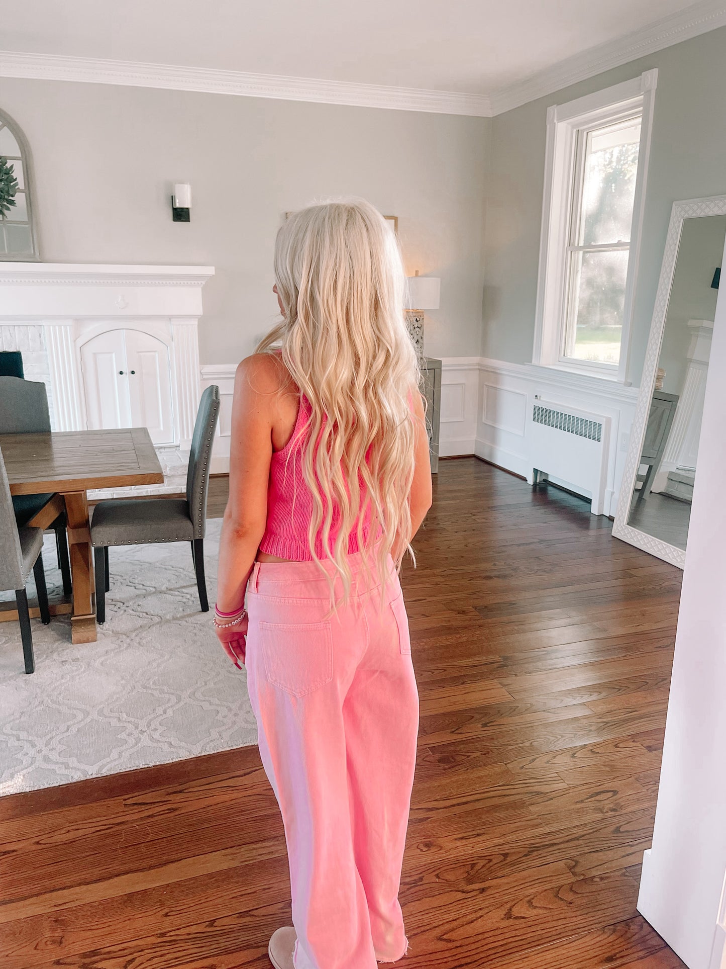 Pink knit vest top styled with pink pants, shown in a home setting.