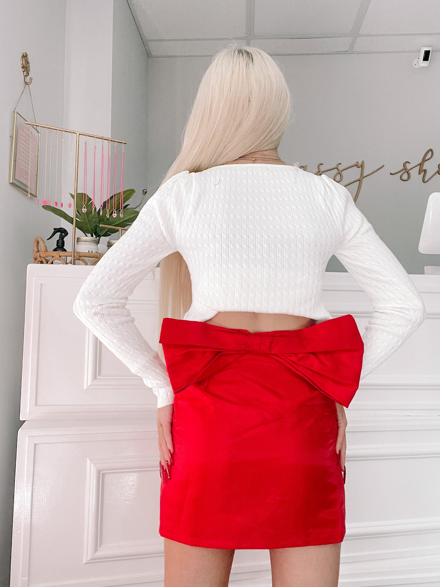 Red satin mini skirt with oversized bow detail, paired with a white knit sweater.