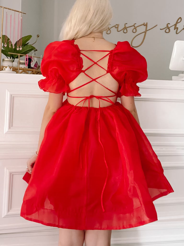 Red organza mini dress with puff sleeves and a crisscross back detail.