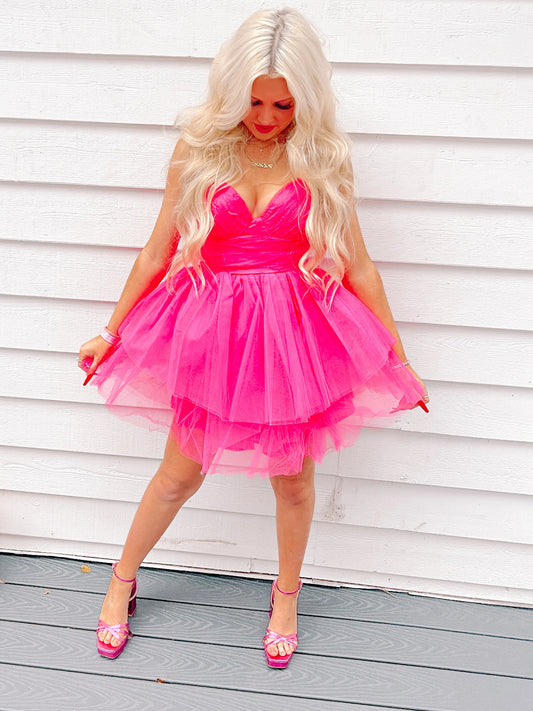 Sassy Shortcake Never Too Late Hot pink tulle mini dress, layered skirt, worn against white wood siding.