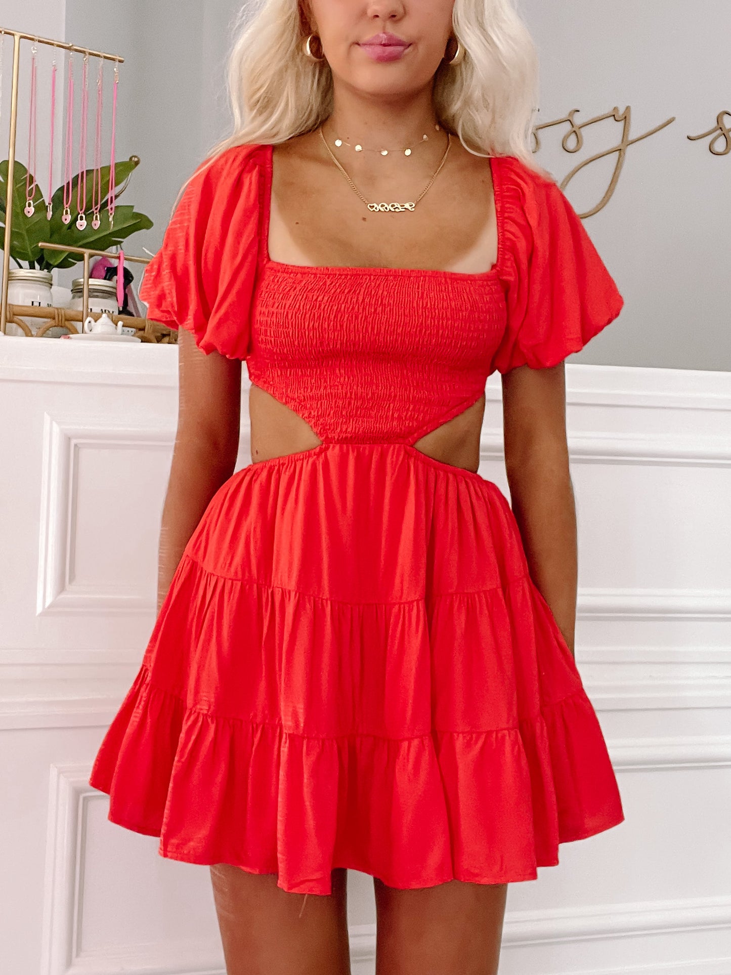 Red tiered mini dress with cutout detail, shown on model against white wall.