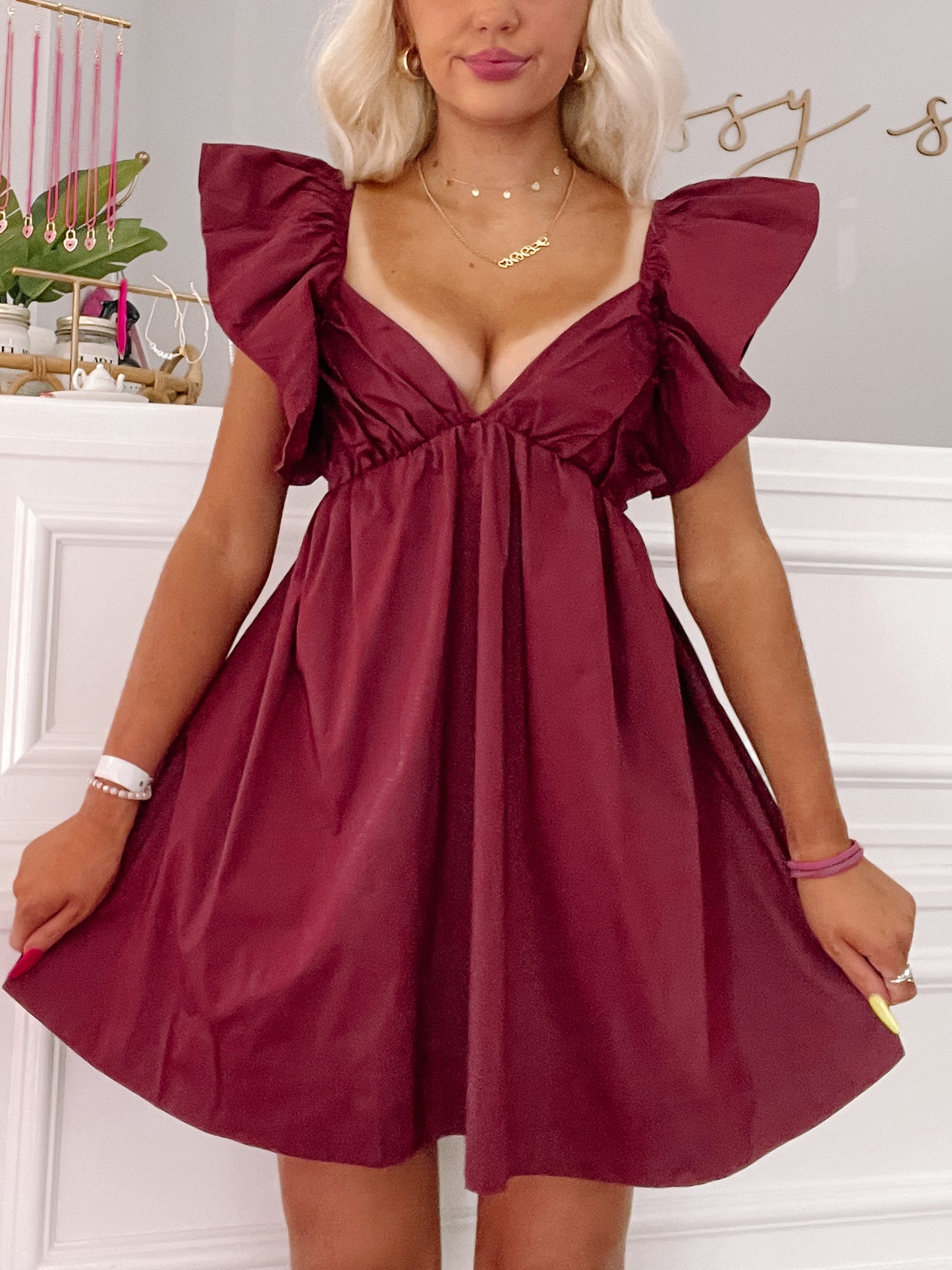 Burgundy mini dress with ruffled sleeves, shown on a model against a white background.