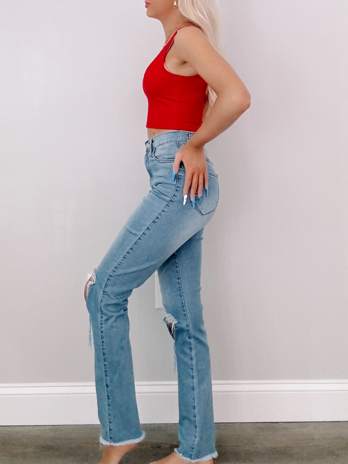 Light wash jeans with distressed knees, shown on a model against a neutral background.