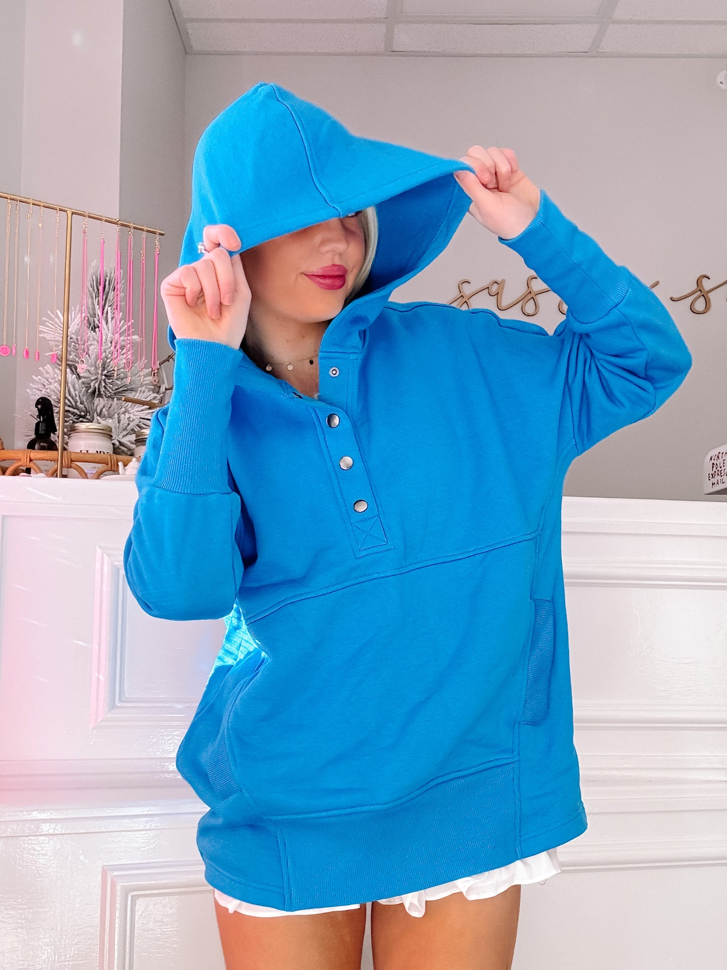 Bright blue pullover hoodie with button placket, modeled indoors.