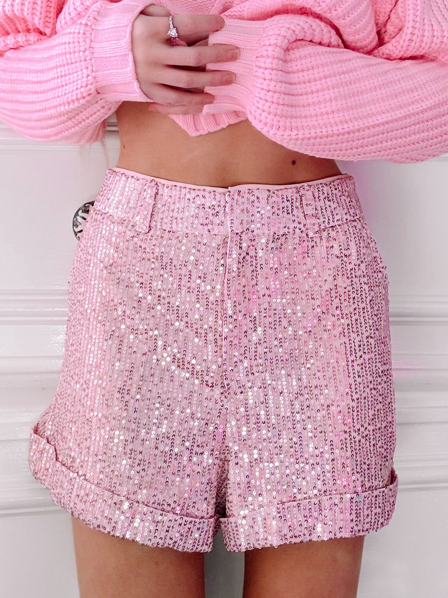 Pink sequin shorts with cuffed hems, shown on a model.