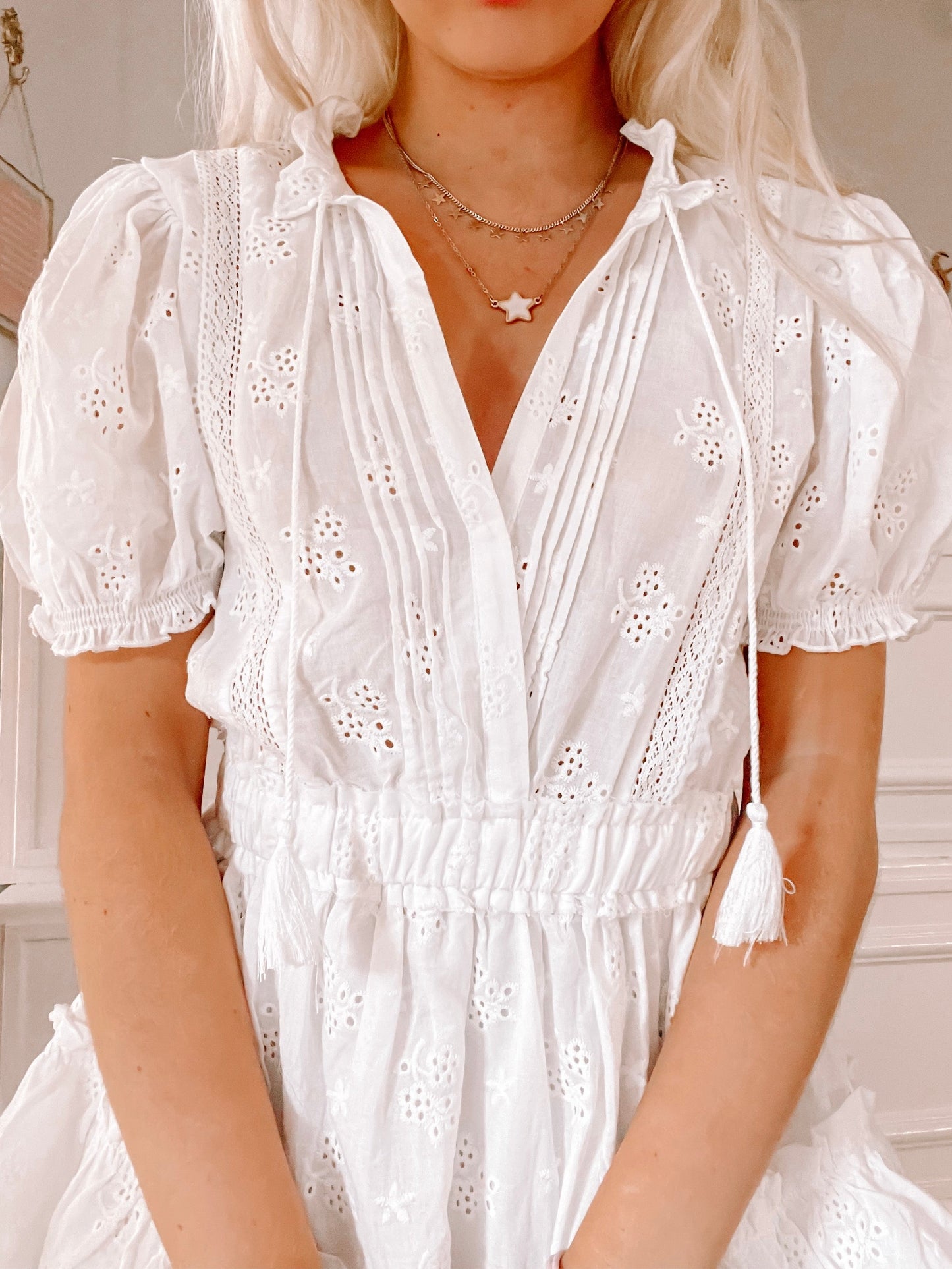 White eyelet mini dress with puffed sleeves and drawstring waist.