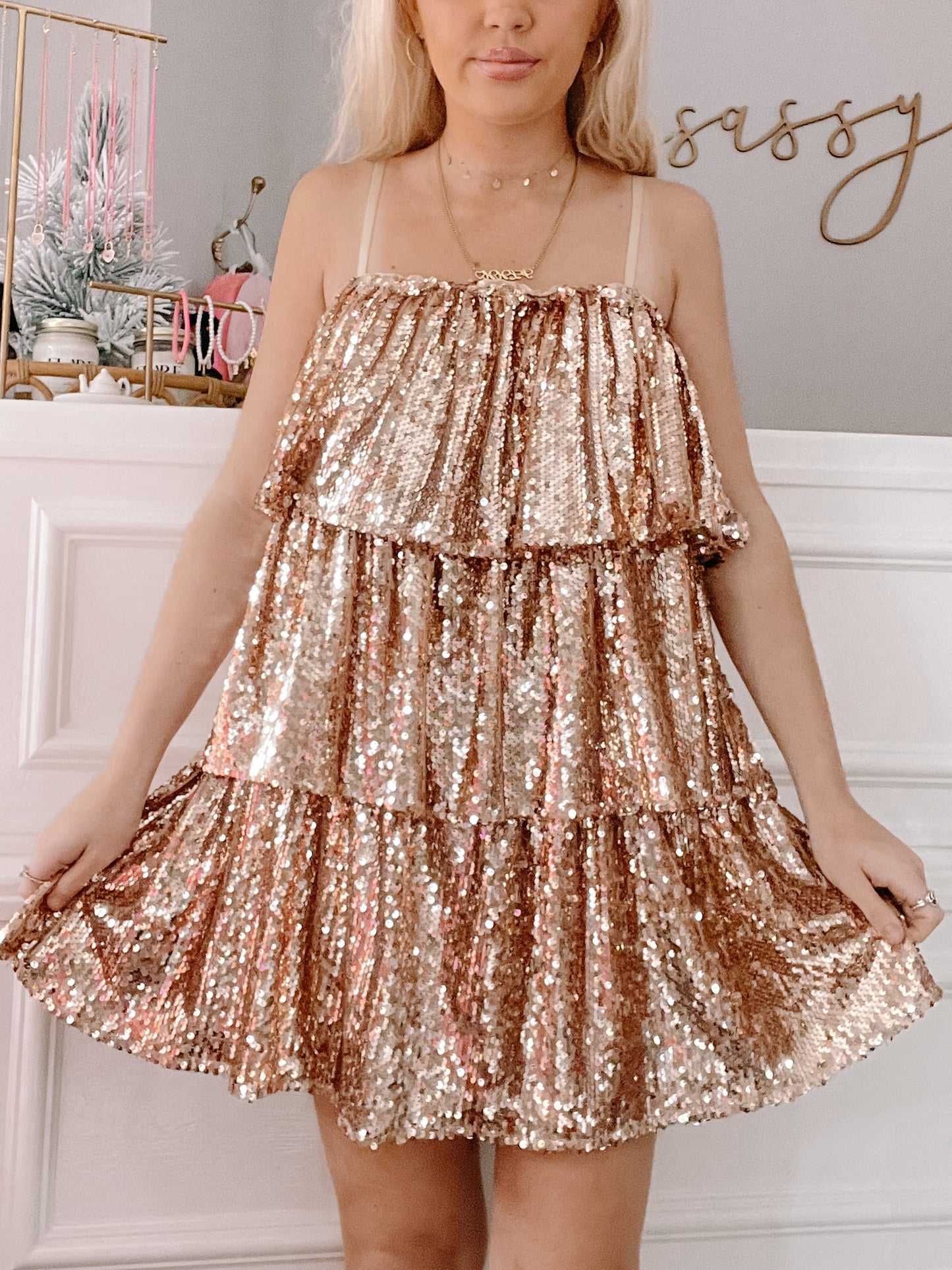 Rose gold sequined mini dress with tiered ruffles, shown on a model against a neutral backdrop.
