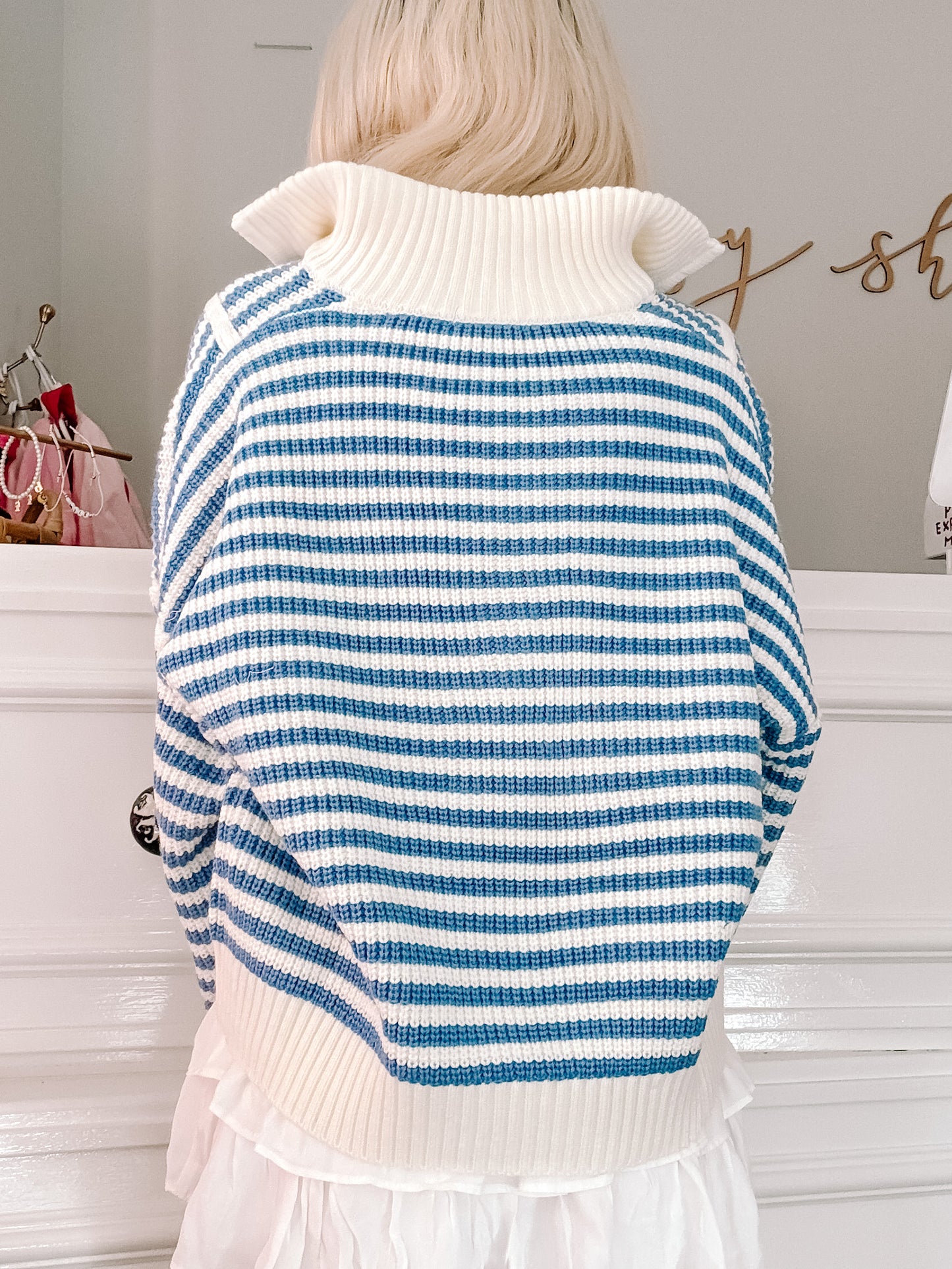 Blue and white striped turtleneck sweater, waffle knit texture, worn over a white ruffle skirt.