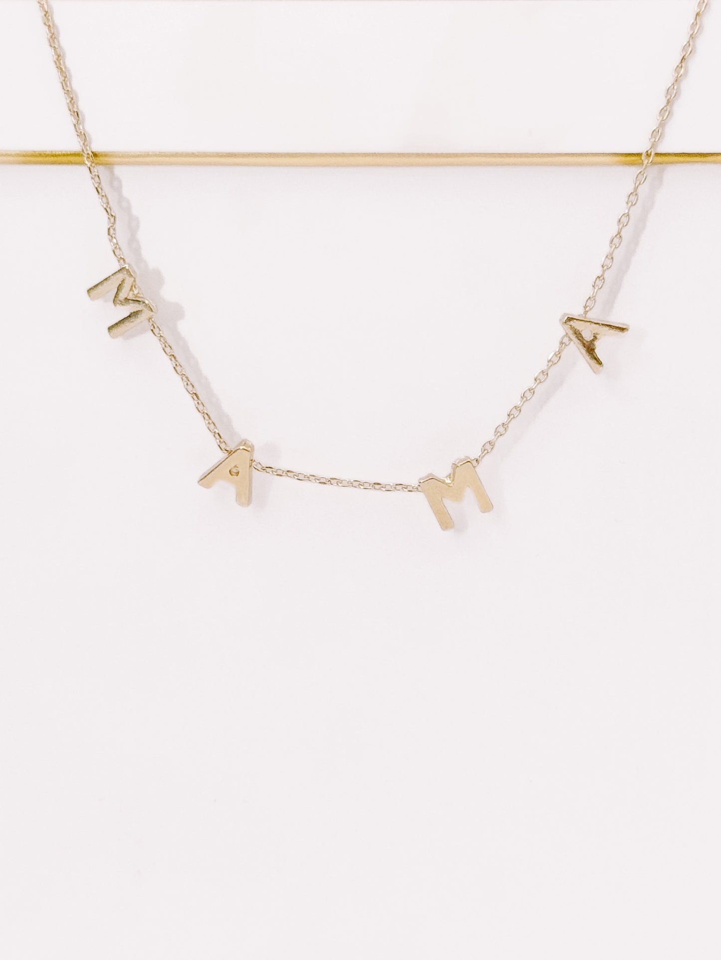 Gold "Mama" necklace on white background, delicate chain.