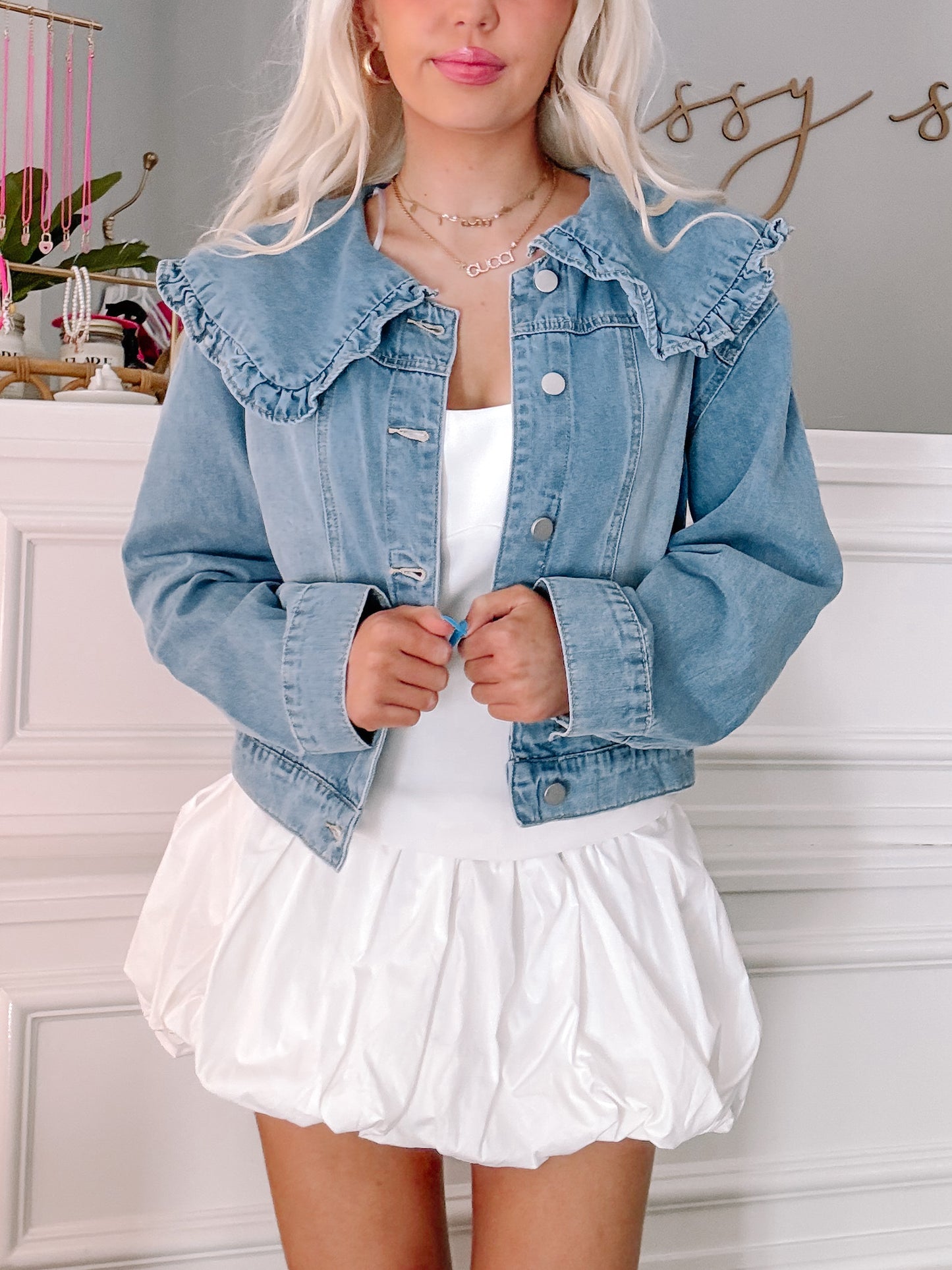 Light wash denim jacket with ruffled collar paired with a white bubble hem mini skirt.