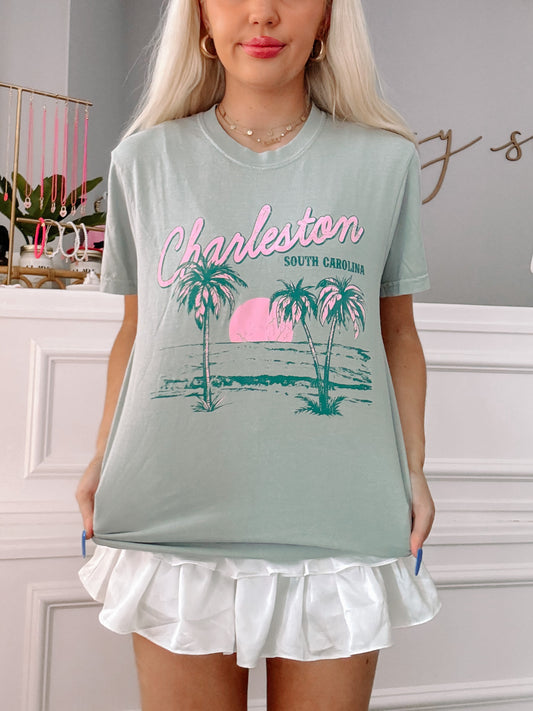 Sage green Charleston, South Carolina tee with palm tree graphic; model wearing a white ruffle skirt.