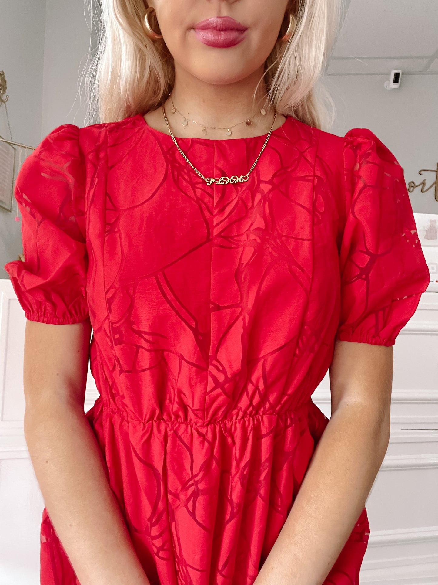 Close-up of a red dress with a subtle pattern, featuring short puff sleeves and a cinched waist.
