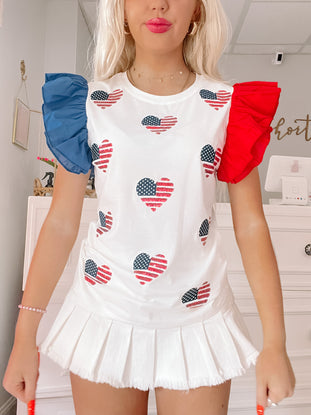 White ruffle top with American flag heart design; red & blue ruffled sleeves.