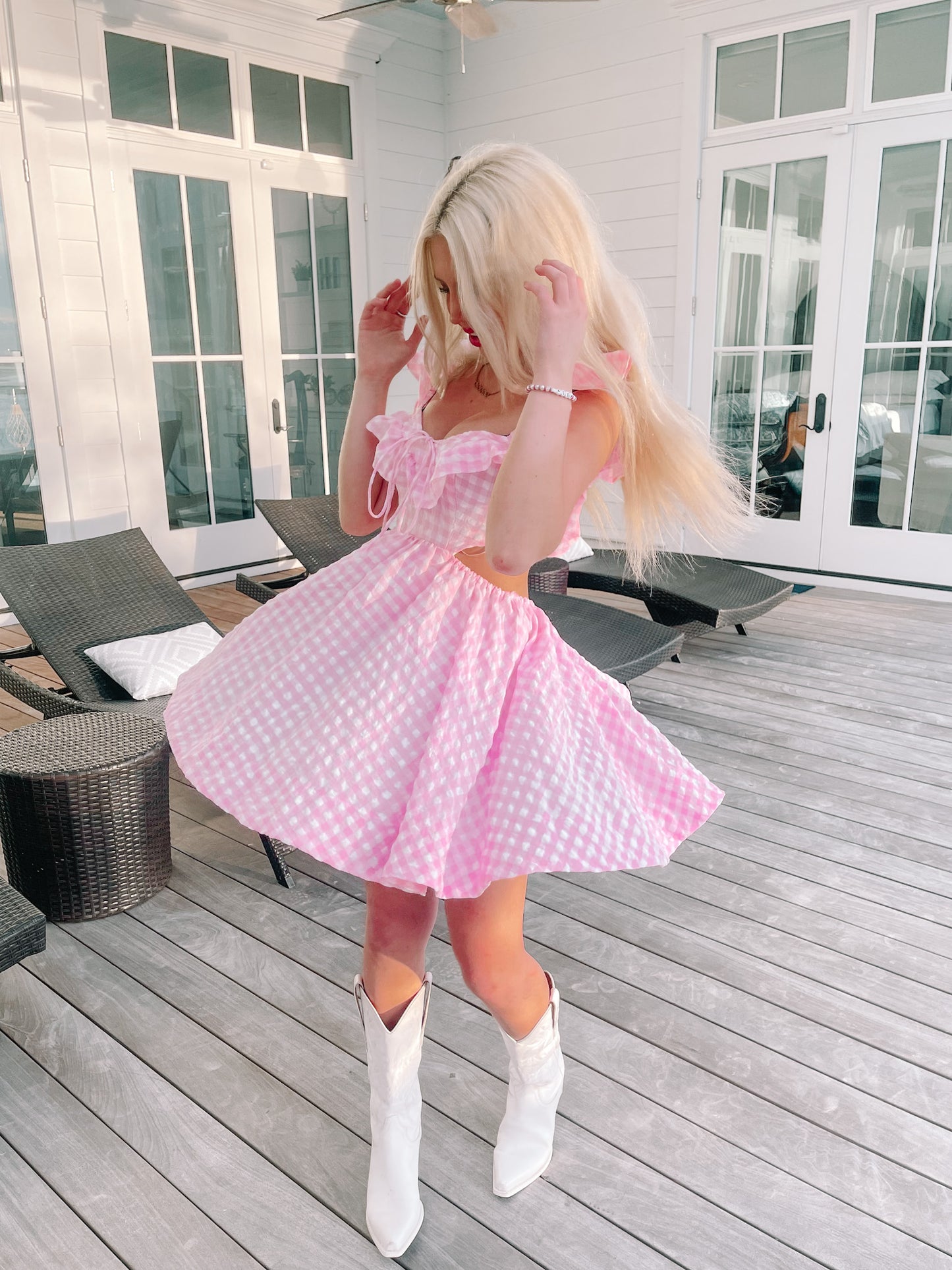 Pink gingham dress twirled outdoors on a wood deck.