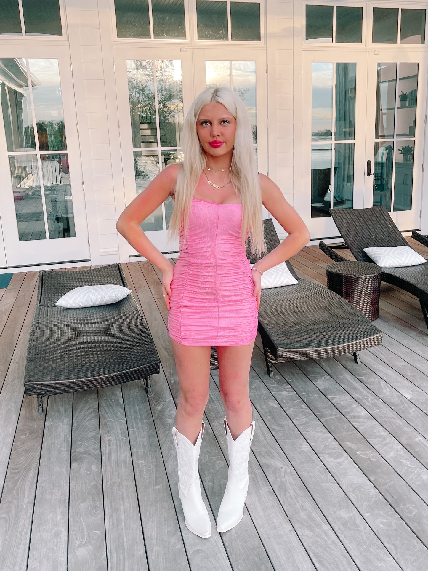 Pink mini dress with a holographic effect, worn outdoors on a patio.