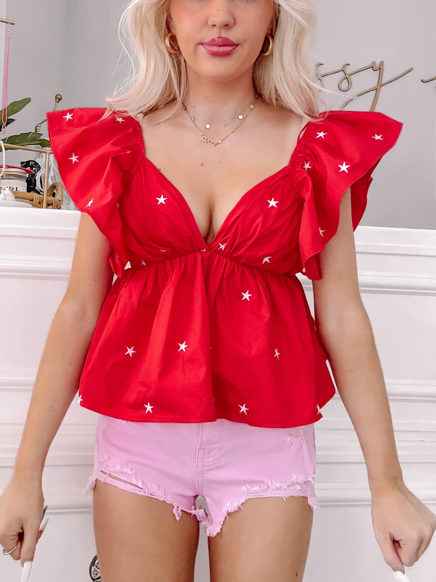 Red star-print blouse with ruffled sleeves, worn with pink denim shorts.