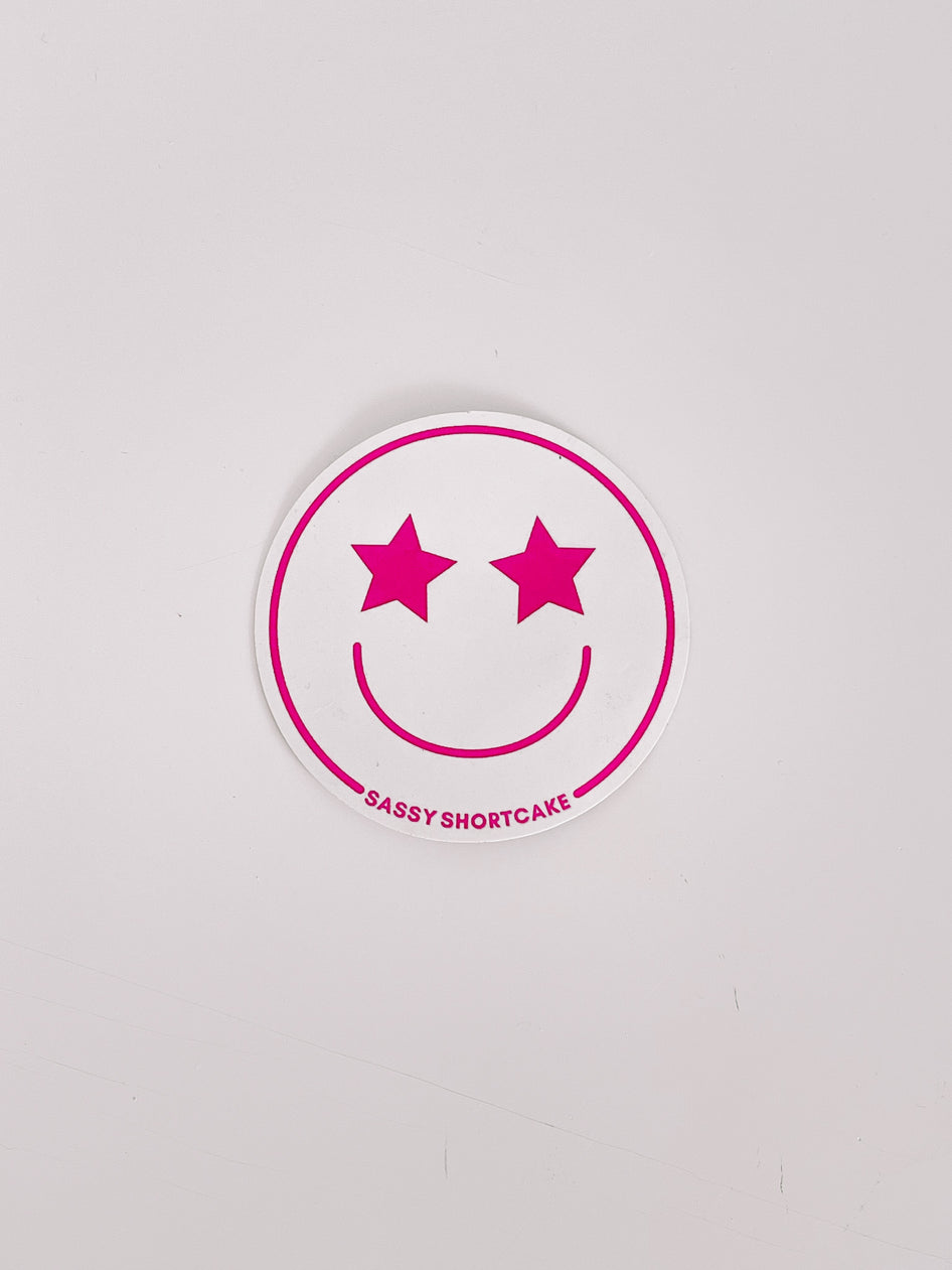 Pink star-eyed smiley face sticker on white background