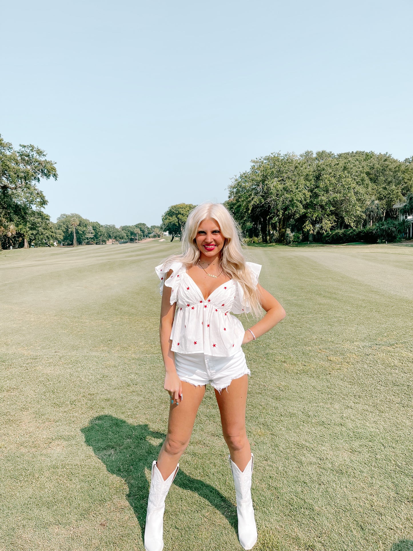 White embroidered star top paired with denim shorts, modeled outdoors on a sunny day.
