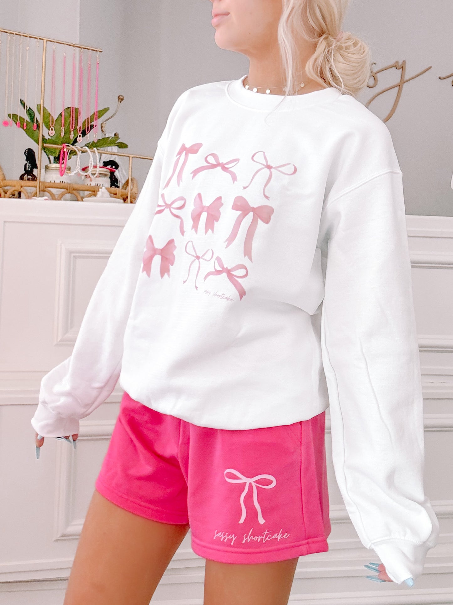 Hot pink shorts with a delicate bow graphic; styled with a matching white sweatshirt.