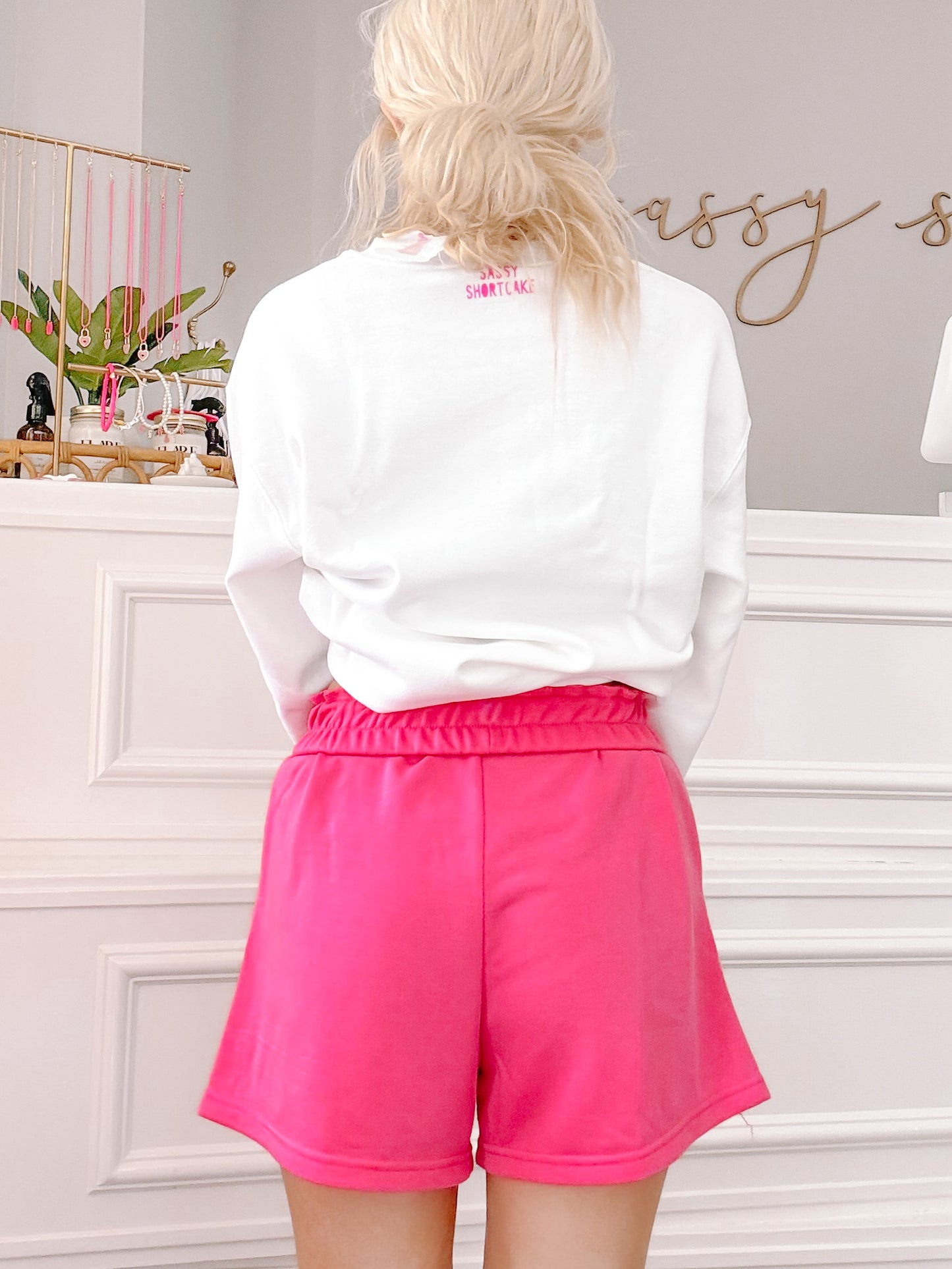 Hot pink pull-on shorts shown from behind against a white wall.
