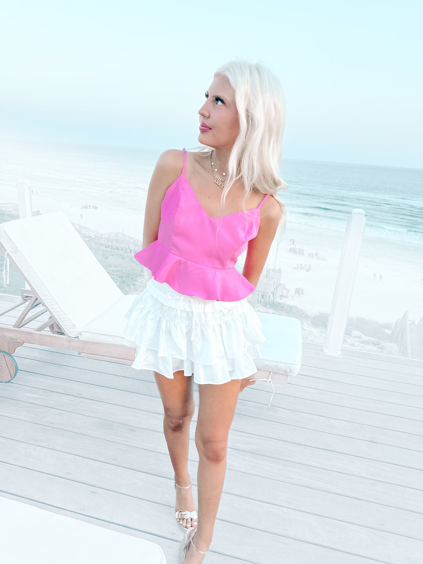 Hot pink peplum top paired with a white tiered mini skirt, beach background.