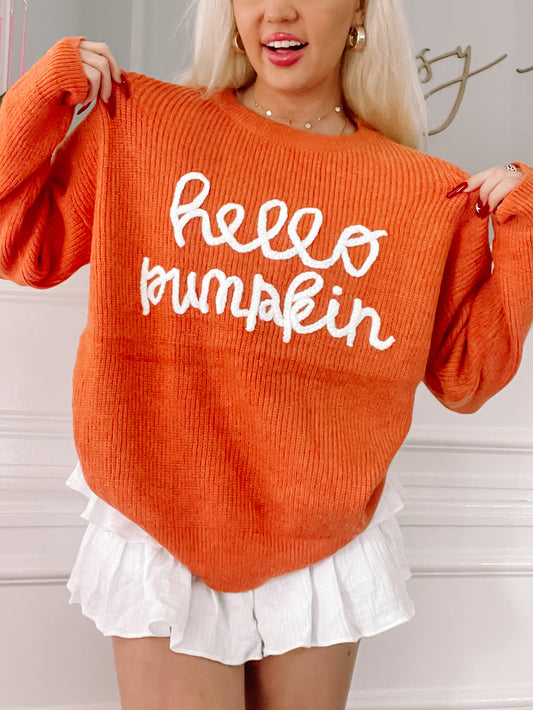 Orange knit sweater featuring a white "Hello Pumpkin" design; fall fashion.