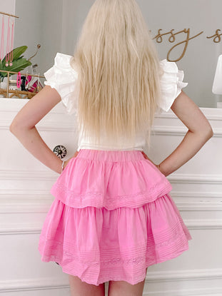 Pink tiered mini skirt with delicate lace trim, shown from the back.