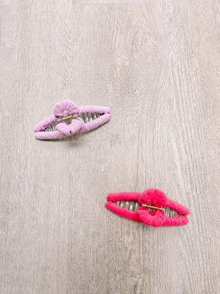 Pink and red fuzzy claw clips on wood background