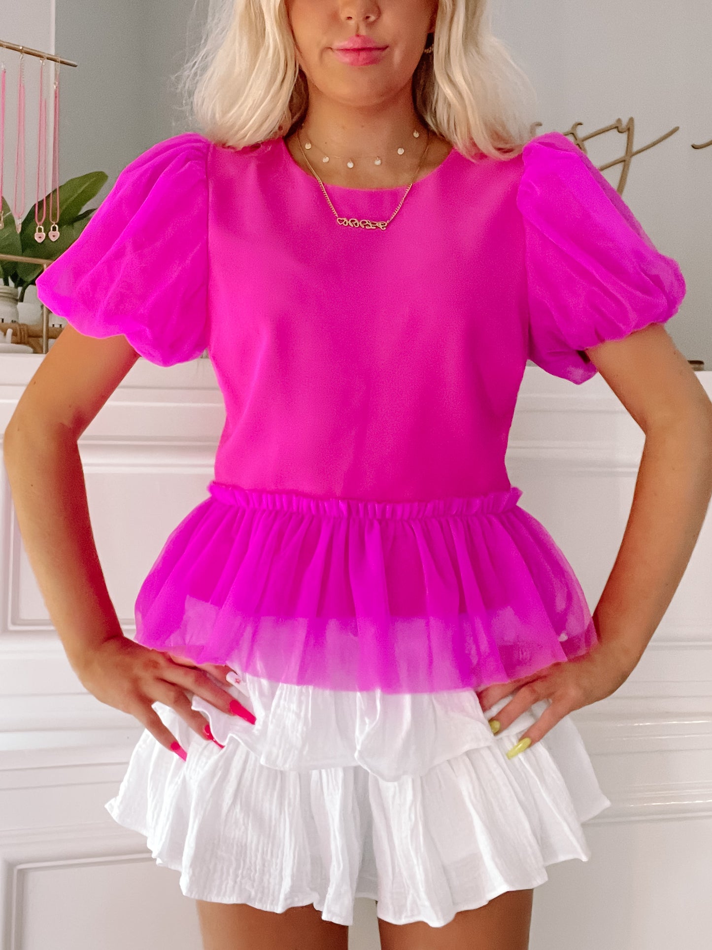 Fuchsia bubble-sleeve top with tiered mesh overlay, styled with a white ruffled skirt.