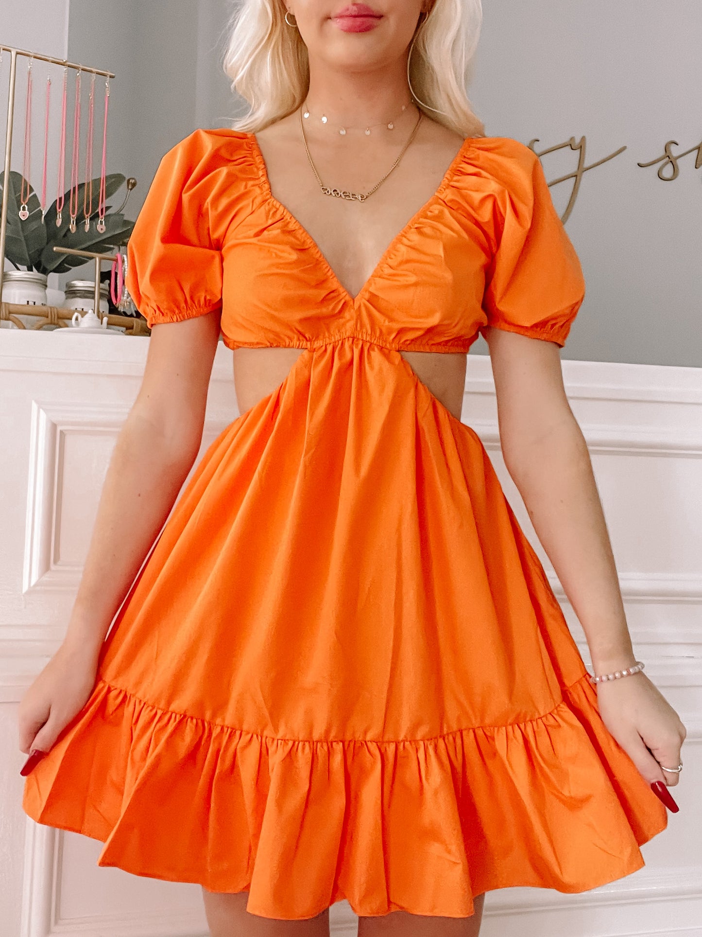 Bright orange mini dress with puff sleeves and a cutout detail, styled against a white background.