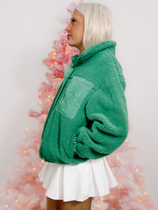 Green sherpa jacket with corduroy detail, modeled against a pink Christmas tree.