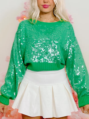 Green sequin sweater with balloon sleeves; festive holiday look.