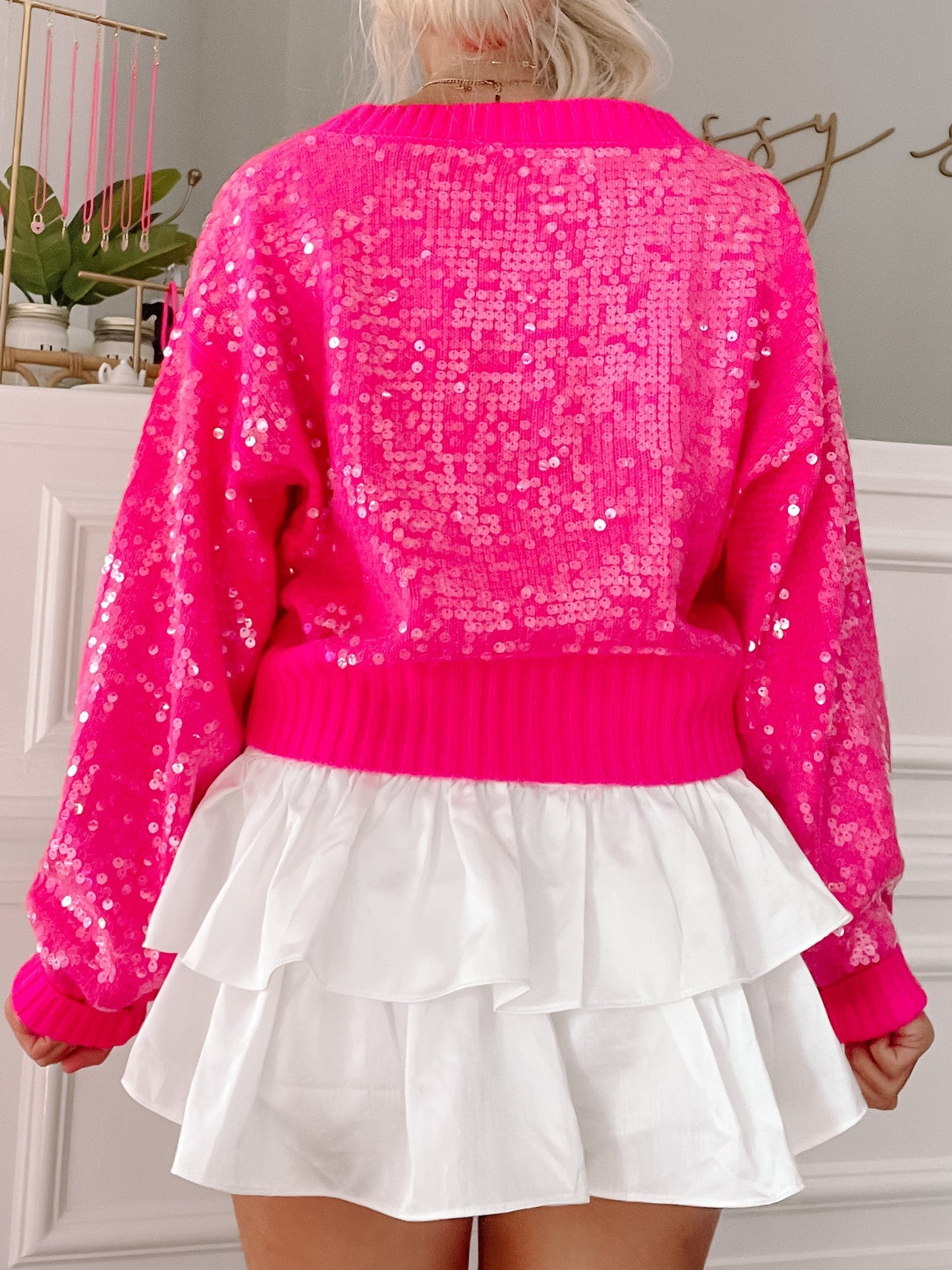 Hot pink sequin sweater with long sleeves and a white ruffled mini skirt.