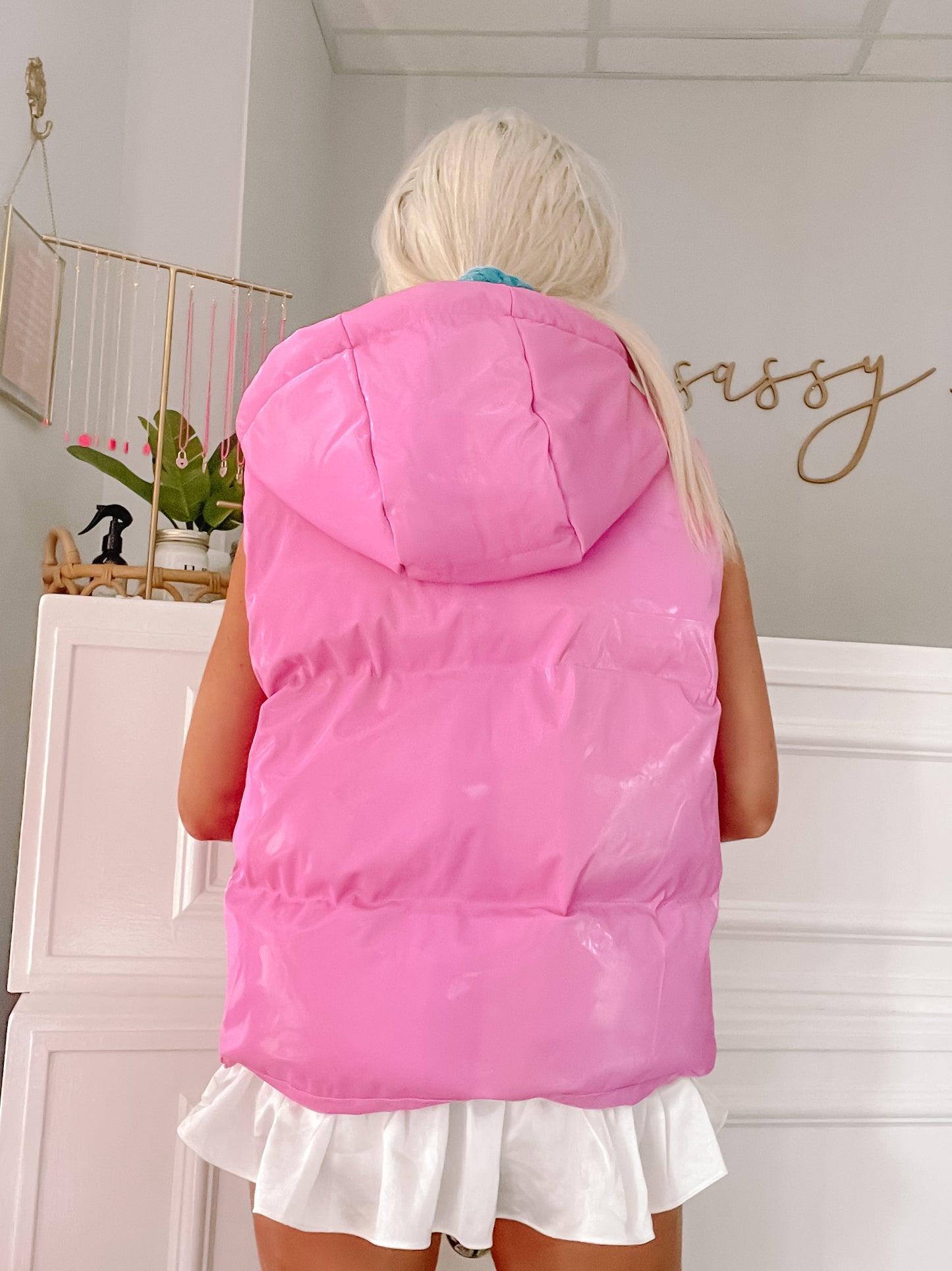 Pink hooded puffer vest with shiny finish, shown from the back.