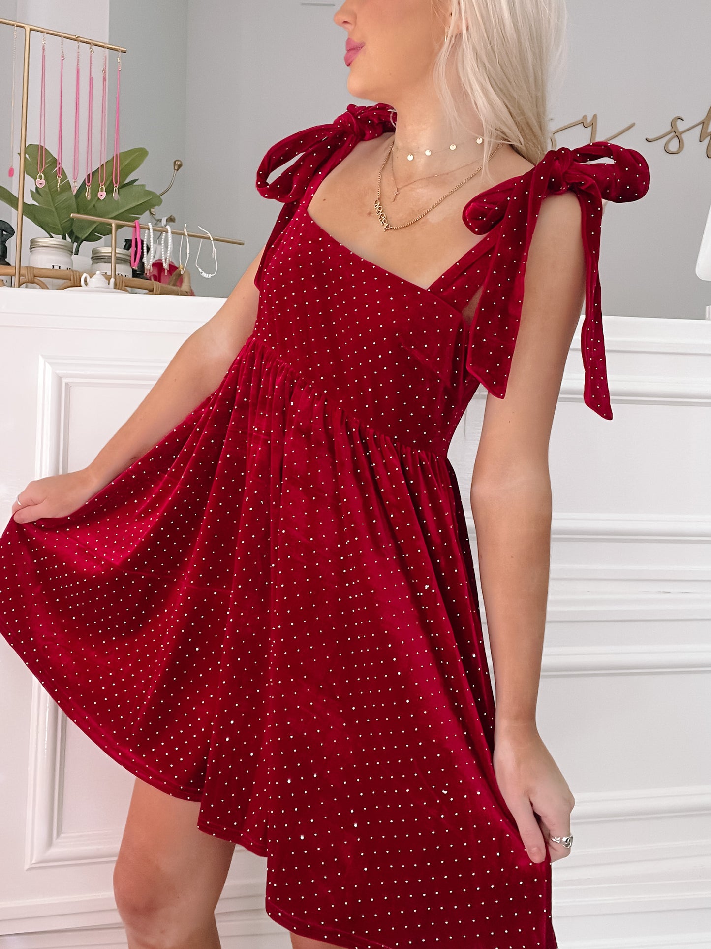 Red velvet mini dress with sparkling embellishments and tie straps, shown on a model.