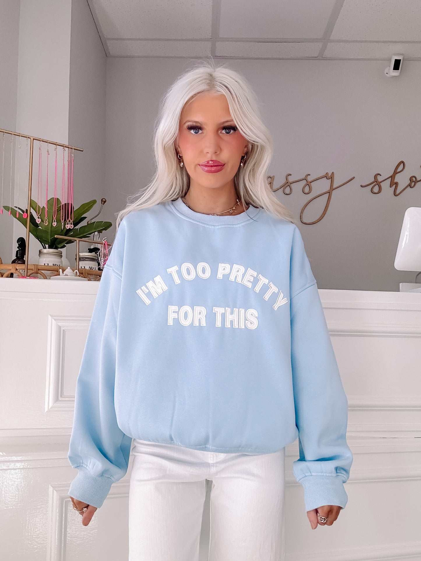 Light blue crewneck sweatshirt with "I'm too pretty for this" text, modeled indoors.