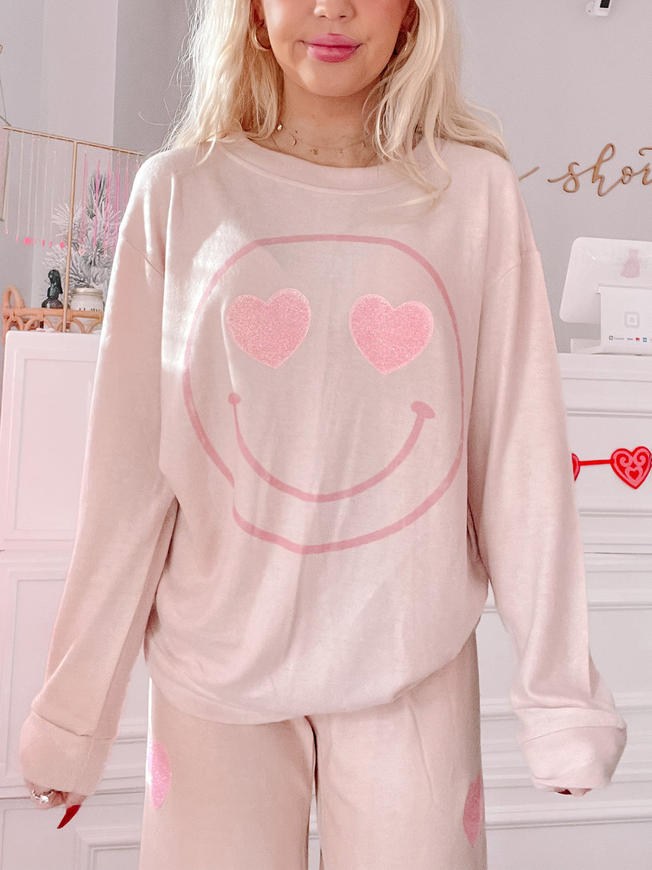 Cozy blush pink pajama set featuring a smiley face with heart eyes; perfect for Valentine's Day.