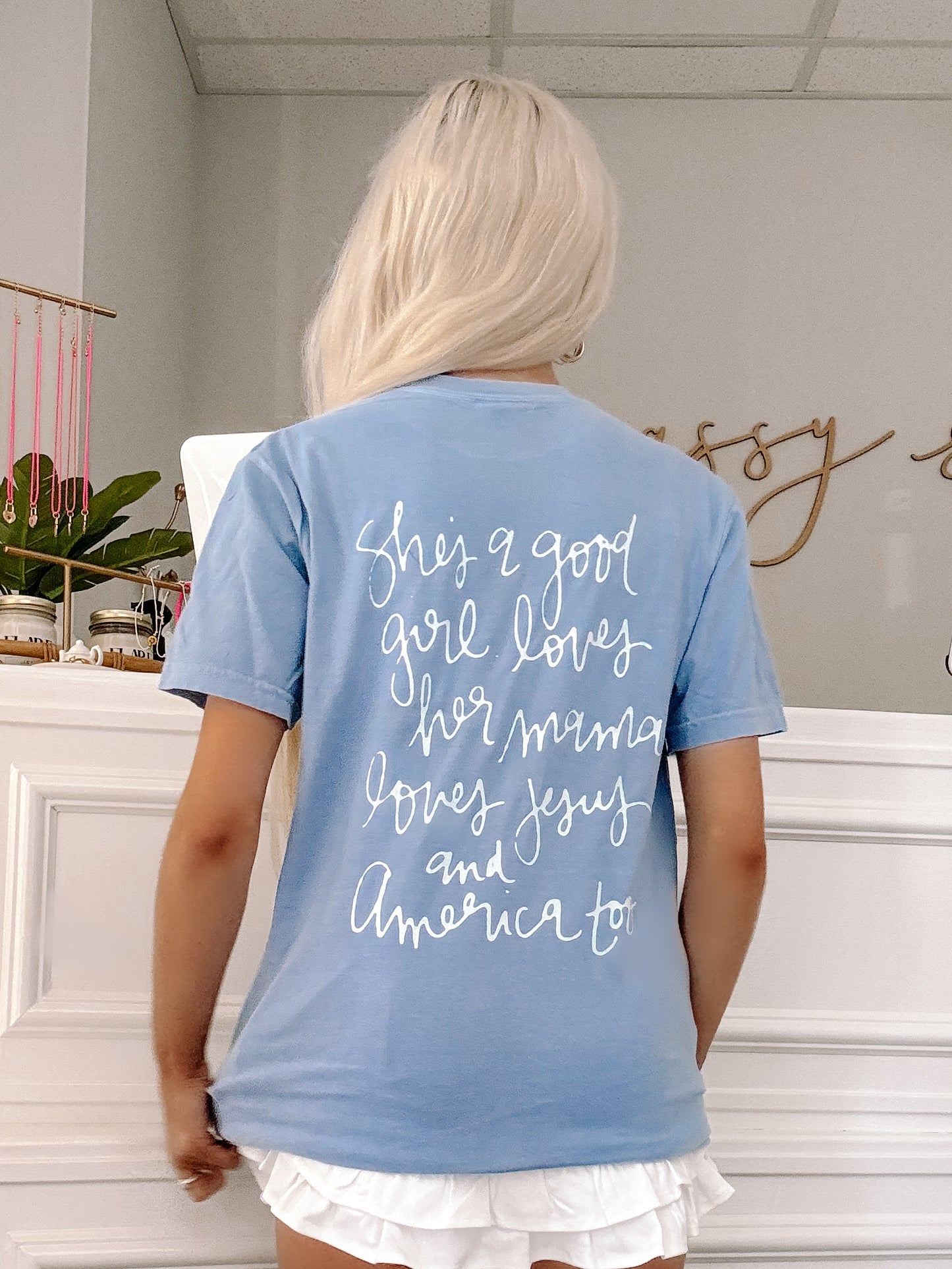 Model wearing blue patriotic tee with “Loves Jesus & America Too” text.