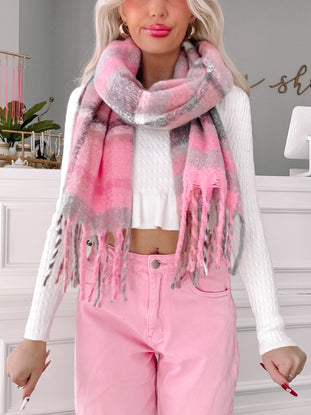 Pink and gray plaid scarf with frayed edges, worn with a white sweater and pink pants.