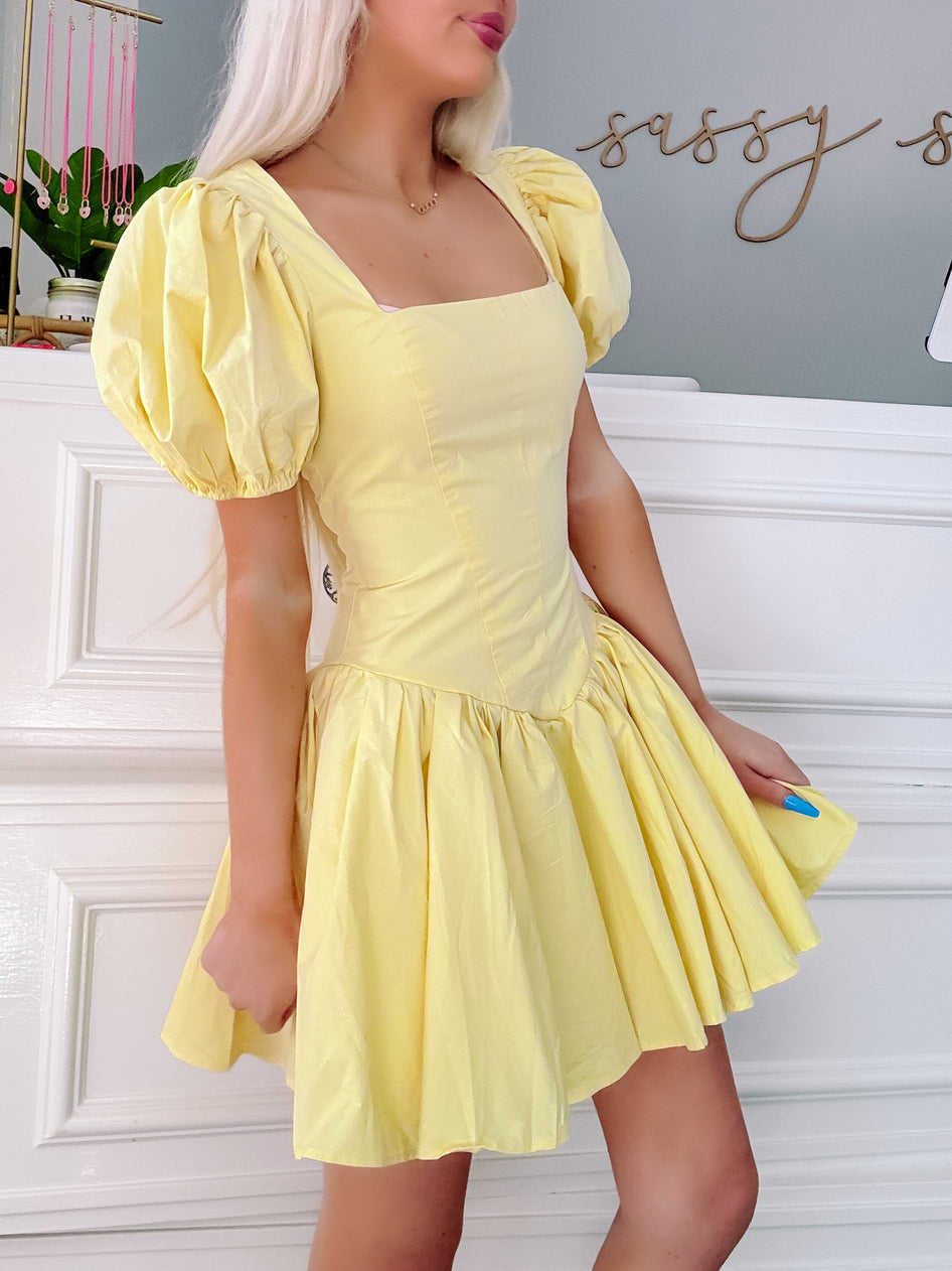 Pale yellow puff-sleeve mini dress, fit-and-flare silhouette, shown on model.